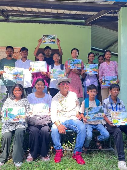 A smaller group of students from the Doomdooma college workshop, sitting together and showing off their beautiful landscape paintings. Each one has a unique touch.