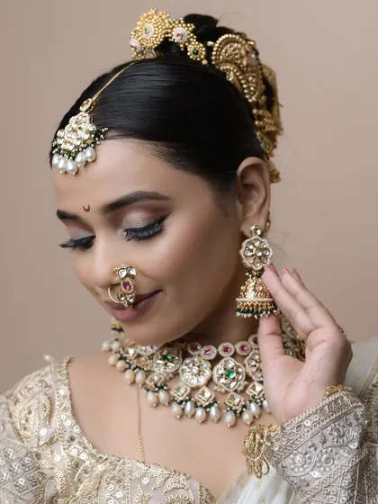 A close-up on the details of the student's work, from the intricate eye makeup to the perfectly placed jewelry and the traditional 'khopa' hairstyle.
