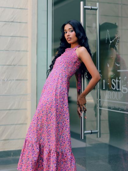 A full-length shot of the same pink dress, taken in an urban setting. The reflection in the glass door adds a modern, editorial touch.