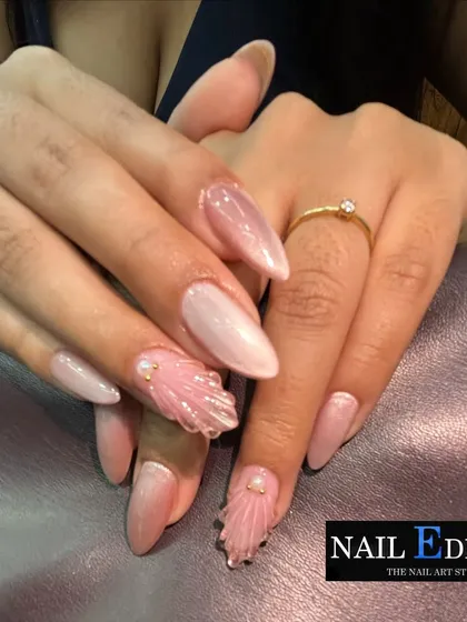 A closer look at our sculpted seashell texture on almond-shaped nails. The delicate ridges and pearl accents create a realistic shell effect, paired with a soft pink cat-eye polish for an ethereal, beachy vibe.