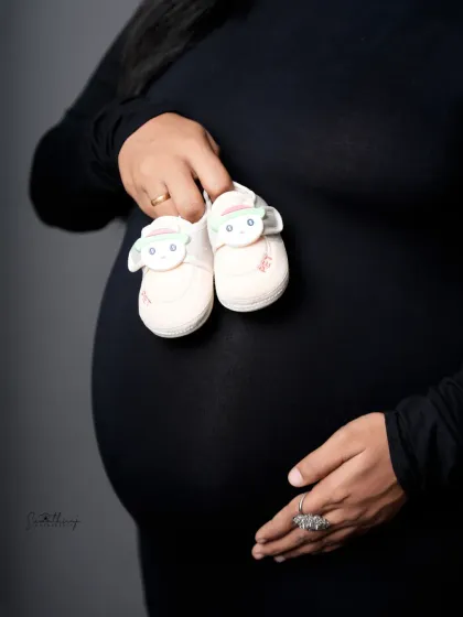 A close-up shot focusing on the baby bump and a pair of tiny shoes. This simple yet powerful image is a beautiful symbol of the new life that is on the way.