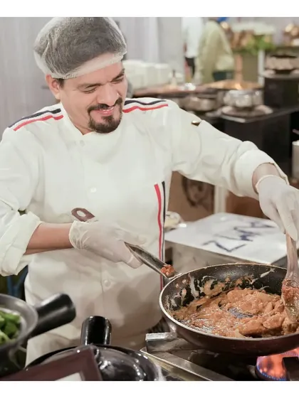 Our chef expertly preparing a dish with a smile at a live station. We pride ourselves on having a professional and engaging team that enhances the guest experience.