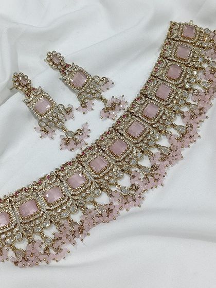 A popular choker design featuring square-cut stones, available in a variety of colors like emerald green, white, aqua blue, and baby pink. The matching earrings complete this elegant and modern ethnic set.