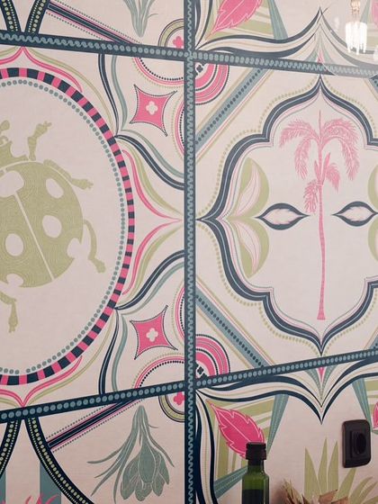 A closer look at the 'Tropical Tapestry' wallpaper. You can see the hand-drawn details in the ladybugs and palm trees, designed to look like individual, colourful tiles that fit together seamlessly.