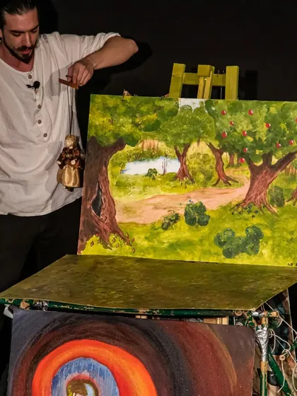 The puppeteer uses a painted backdrop to create a new location for his marionette in 'Dragon and the Devil'.