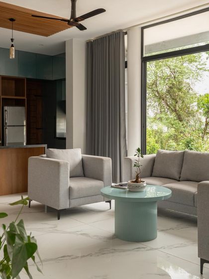 A simple yet elegant living space in the 'Bodhisatwa' home, where neutral-toned furniture is complemented by views of the outdoor greenery.