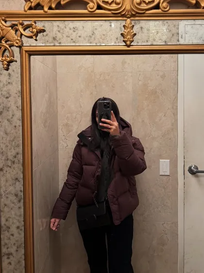 A mirror selfie in a stylish bathroom, showing off a winter puffer jacket.