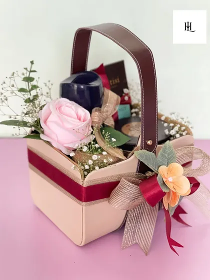 Small in size, big on joy. This mini hamper in a leather-handled basket is packed with gourmet treats and a real bloom, proving that the smallest gifts can make the biggest impact.