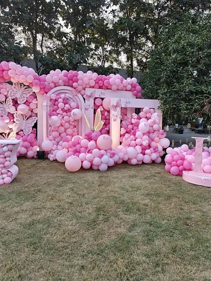 A wide shot of our stunning outdoor pink butterfly-themed installation. The setup includes multiple arches and a balloon-filled table, creating an immersive environment that transforms a simple lawn into a fairytale wonderland.