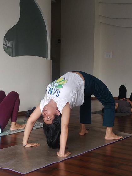 A student practices the wheel pose during a hip-immersive class. This highlights our focus on specific themes within our regular sessions to deepen understanding of the body.