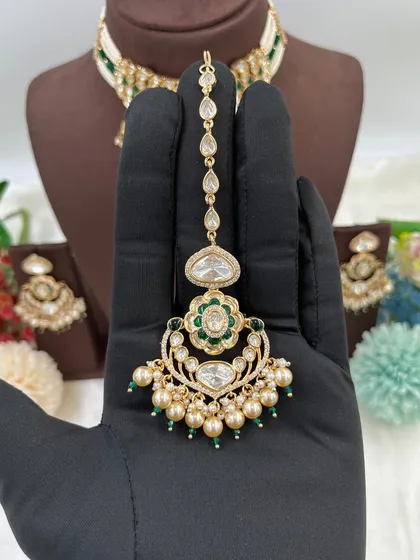 The 'Darbaar' premium maang tikka with green accents and pearls.