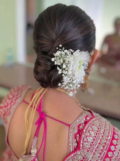 A classic bun with a simple arrangement of white flowers and baby's breath. This is an elegant and understated choice.