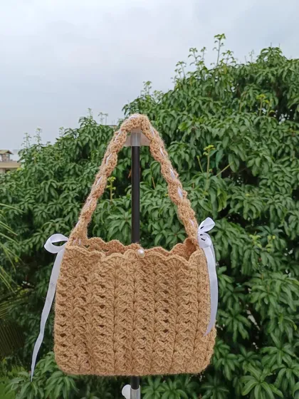Another view of the brown shoulder bag, showcasing the scalloped top edge and sturdy, braided handle.