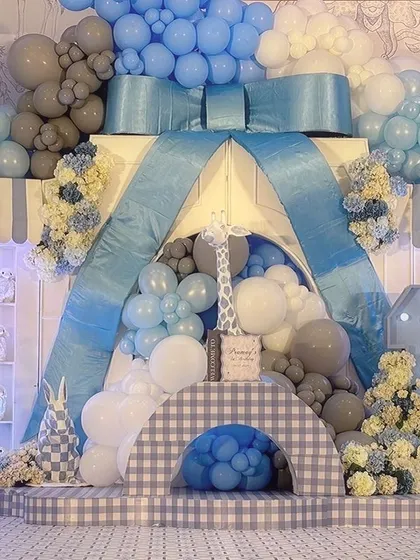 A frontal view of the main stage, where a giant blue bow serves as the centerpiece for the balloon and floral arrangements.