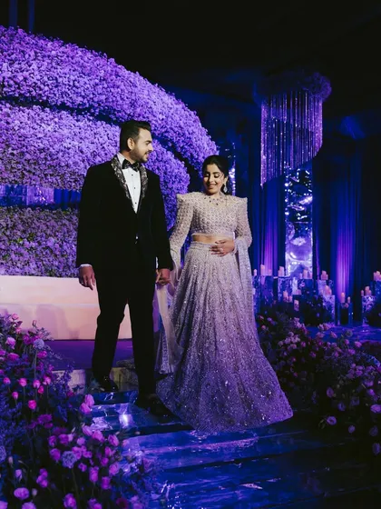 A full view of the magnificent stage and decor. We capture the couple within this grand setting, showcasing the scale and beauty of their celebration.