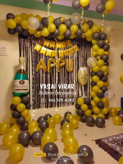 It's party time. This fun and stylish setup for an adult birthday features a black and yellow balloon arch against a silver fringe curtain, complete with champagne bottle and glass foil balloons to set the mood.