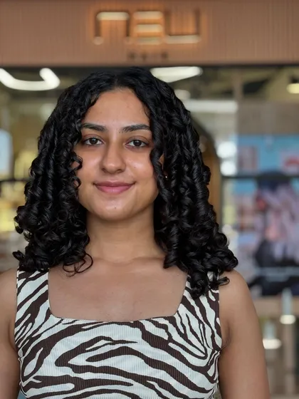 A happy client showing off her fresh, defined curls after a custom cut and style. The shape is designed to be manageable and look great with minimal effort at home.