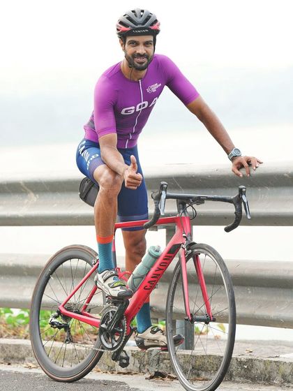 A moment of rest and confidence. A member of the Goan cycling team gives a thumbs up while posing with his Canyon road bike after a tough practice session.