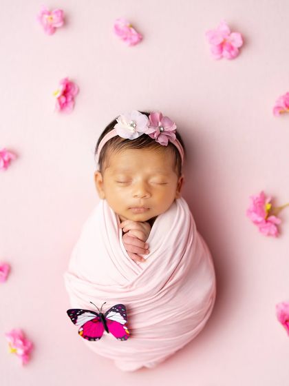 A simple and sweet setup with a baby wrapped in pink, accented with a single butterfly. Sometimes the smallest details make the biggest impact.