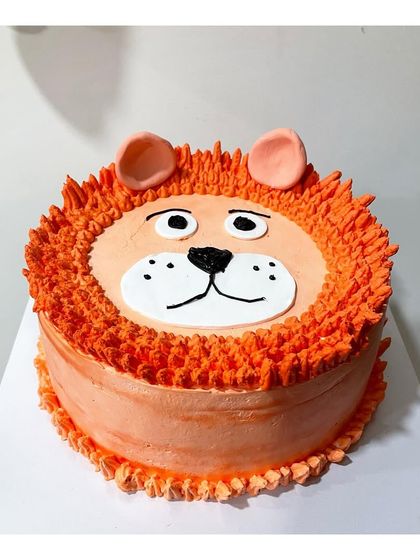 A cute and friendly lion face cake made with orange-colored whipping cream and simple fondant details. A great choice for a jungle-themed party.