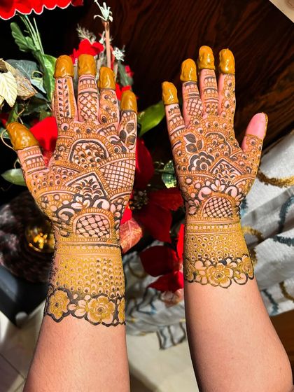 This bridal design features a lovely floral cuff at the wrist and detailed patterns covering the entire hand. The fingertips are coated in henna for that deep, traditional stain.