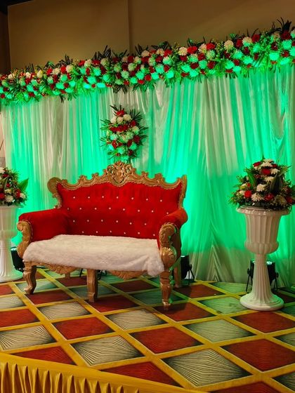 A simple yet elegant stage setup with a bold red sofa as the centerpiece. The green uplighting on the backdrop provides a vibrant contrast, making this a great option for a reception or anniversary party.
