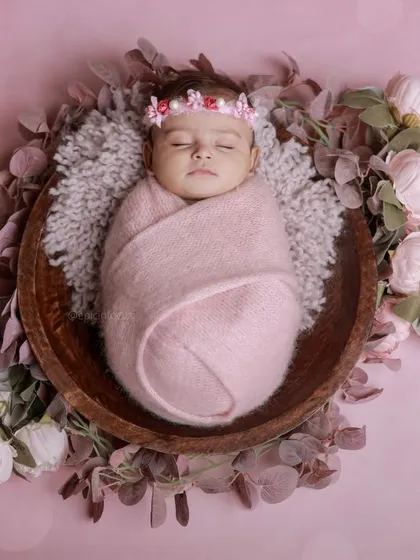 A classic posed newborn session featuring a baby girl swaddled in pink and surrounded by delicate flowers. This highlights our skill in creating elegant, floral-themed portraits in our comfortable studio.