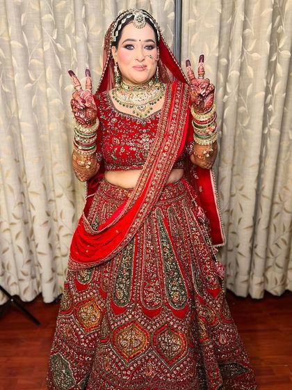 A fun and happy shot of the same bride, showing her playful personality. The full lehenga is visible, and she looks absolutely stunning.