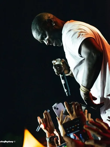 Akon connects with his fans in Bangalore, leaning over the stage as a sea of phones captures the moment. This image highlights the intimate bond between a global superstar and his audience.
