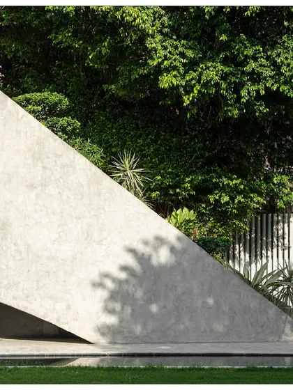 The concrete form of the villa acts as a backdrop to the rich greenery of the site. The design uses simple, powerful gestures to create a harmonious relationship with nature.