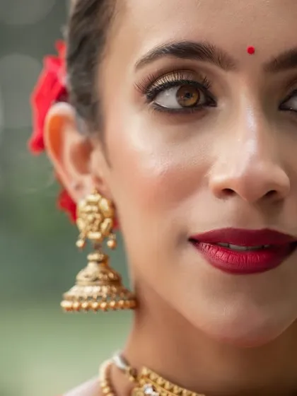 A stunning close-up from a commercial shoot, focusing on the model's expressive eyes and traditional gold jhumkas.