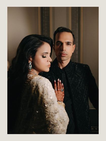 A sophisticated and stylish couple portrait. The contrast between her white gown and his black suit, combined with their confident poses, creates a modern and powerful image.