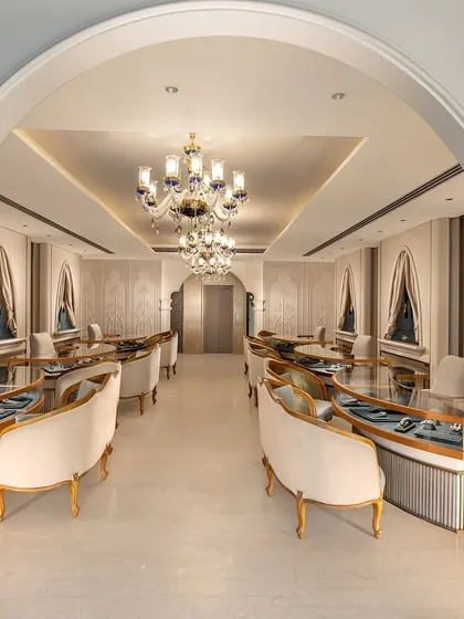 I designed this luxury jewellery showroom to be a masterpiece of classic elegance. The interior view showcases bespoke curved seating, grand chandeliers, and arched entryways that frame the space, creating an exclusive and sophisticated environment for a high-end retail experience.