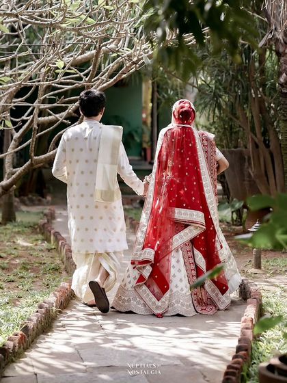 A romantic shot of a couple walking away hand-in-hand down a tree-lined path.