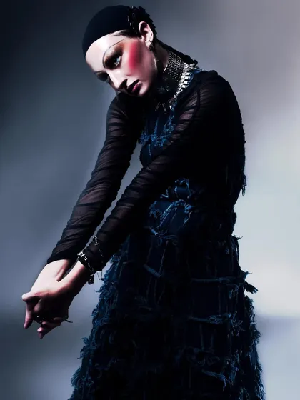 A high-fashion portrait from a collaborative editorial, featuring a textured denim dress and dramatic makeup. The pose and intense lighting create a moody, couture feel.