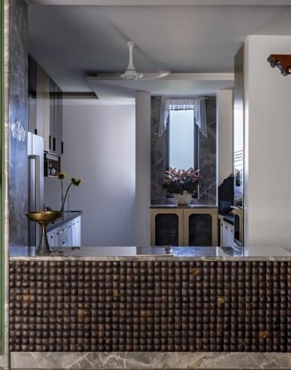 Here, I blended Indian and English design traditions in a 3800 sq. ft. home. A stunning South Indian-style wooden pillar masterfully partitions the open kitchen and bar from the dining area, marrying craftsmanship with contemporary flair.