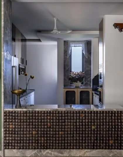 Here, I blended Indian and English design traditions in a 3800 sq. ft. home. A stunning South Indian-style wooden pillar masterfully partitions the open kitchen and bar from the dining area, marrying craftsmanship with contemporary flair.
