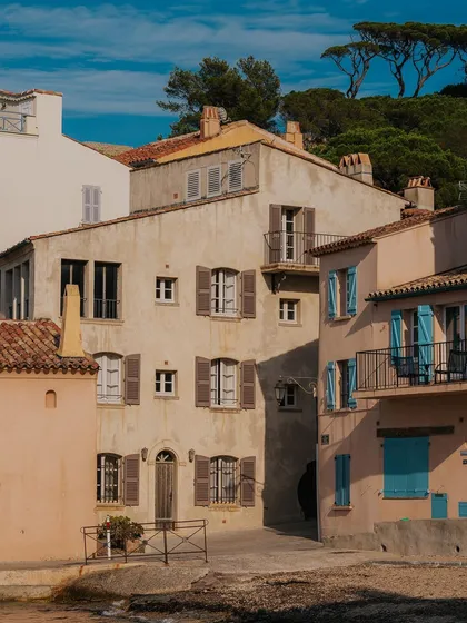 The charming, sun-drenched architecture of St. Tropez's old town. The pastel colors and blue shutters are iconic to the region.