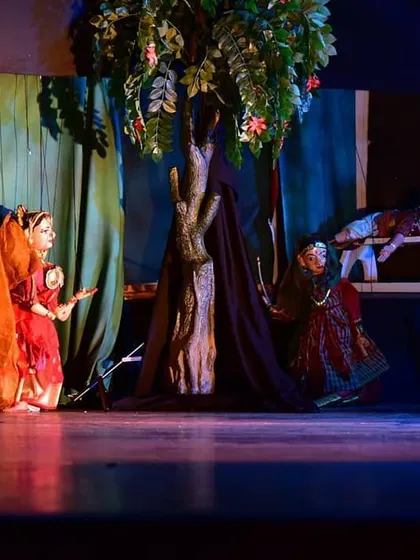 A scene set under a tree, where puppets interact in a naturalistic setting. The stage design is crucial for telling the story and creating a believable world for the characters.