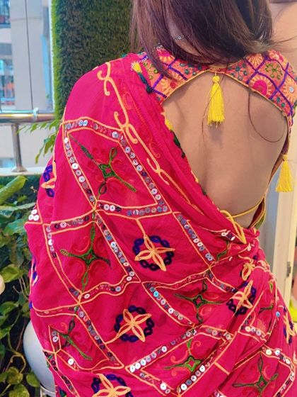 A back view of the pink and orange mirror work blouse, showing the beautiful backless design with yellow tassels.