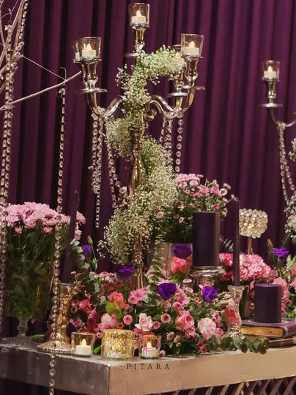 A stunning display where golden candelabras are intertwined with baby's breath and pink florals, set against a backdrop of shimmering crystal strands. This brings both light and life to the decor.