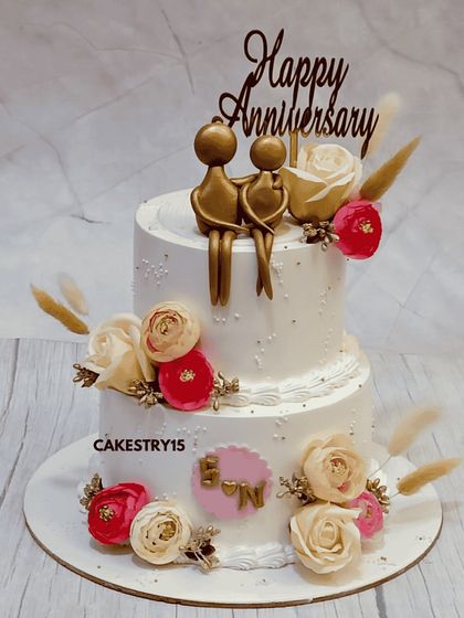 A romantic two-tier chocolate anniversary cake. This 3kg cake is adorned with fresh roses and features a golden silhouette topper of a couple, celebrating their love story.