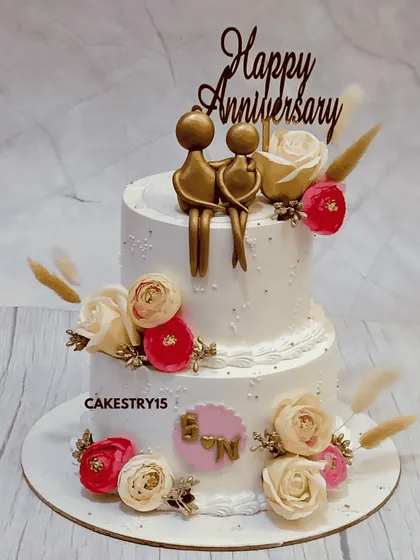 A romantic two-tier chocolate anniversary cake. This 3kg cake is adorned with fresh roses and features a golden silhouette topper of a couple, celebrating their love story.
