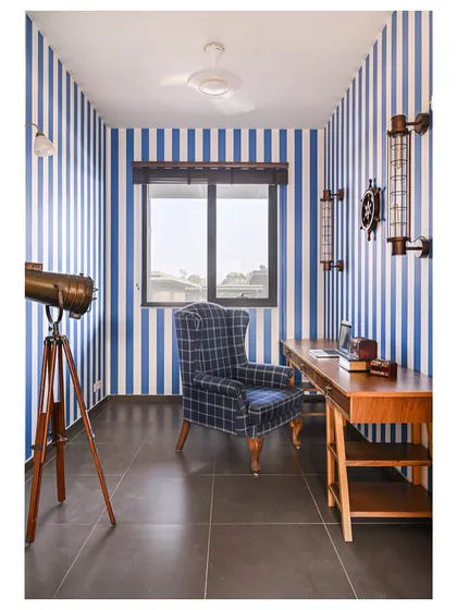 A home should reflect the people who live in it. For a Merchant Navy officer, we designed this study with vintage sailor vibes, using blue and white striped wallpaper, a custom 9-foot desk, and bronze marine accessories.