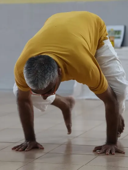 A teacher demonstrates a variation of the peacock pose, showing the immense core and arm strength developed through years of dedicated practice.