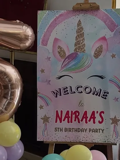 A welcome sign for a unicorn party, paired with a large foil number '5' balloon to highlight the milestone.