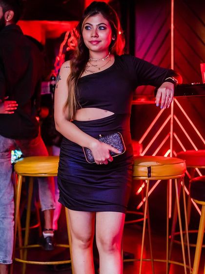 A guest in a stylish black dress, posing by the bar.