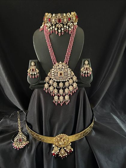 This red Victorian bridal set is perfect for a glamorous reception look. It includes a choker, a long beaded necklace, earrings, maang tikka, and a simple vaddanam.