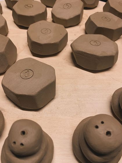 More of the faceted, stamped pieces, along with some small, stacked sculptures, all in their raw clay state.