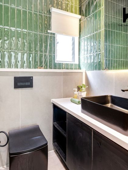 The bathroom in the 240 sq. ft. pod is a statement in style. It features vibrant green subway tiles, a sleek black vessel sink, and a wall-mounted toilet, proving that even small bathrooms can be luxurious.